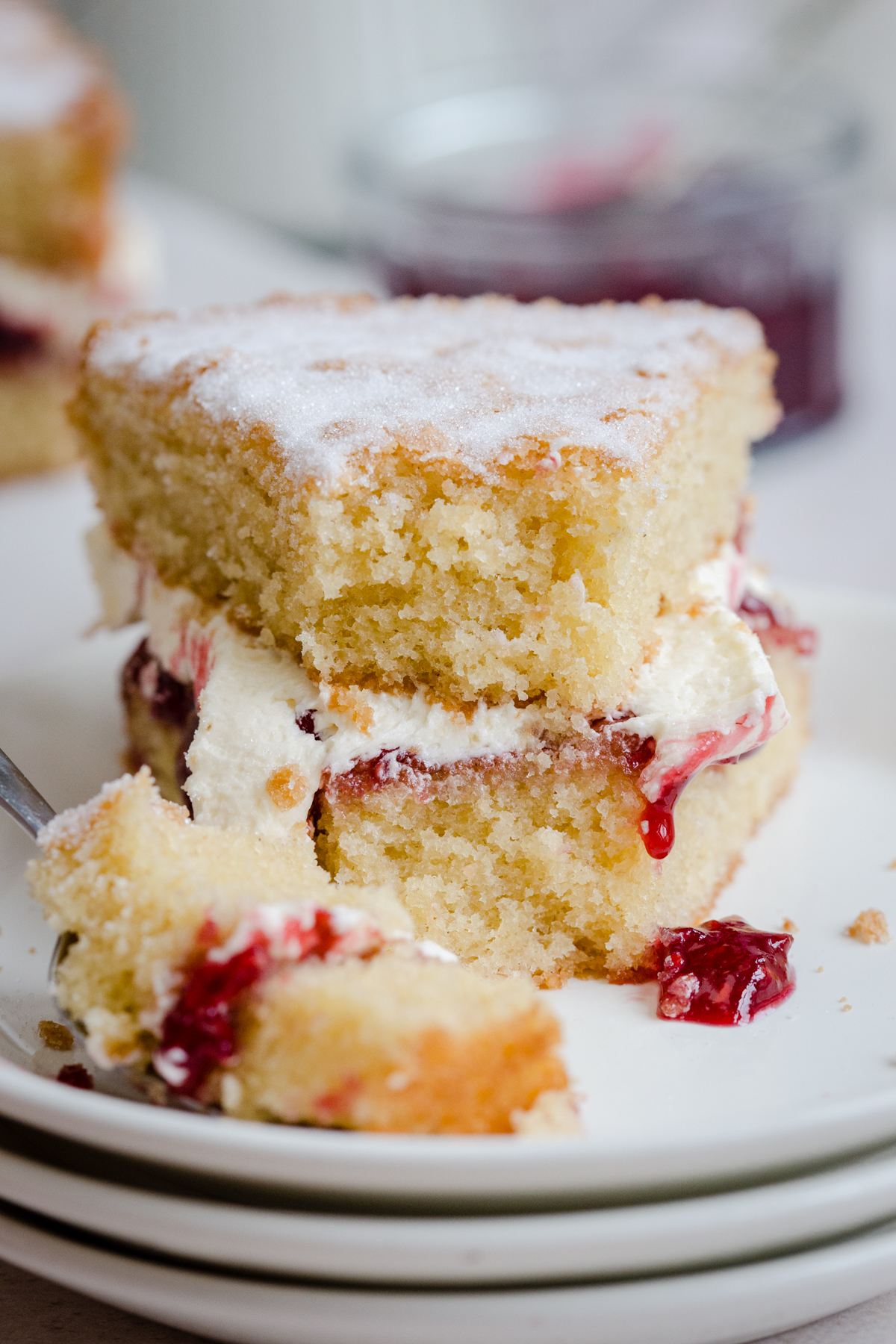VICTORIA SPONGE ON LAYERED PLATES WITH FORKFUL TAKEN OUT